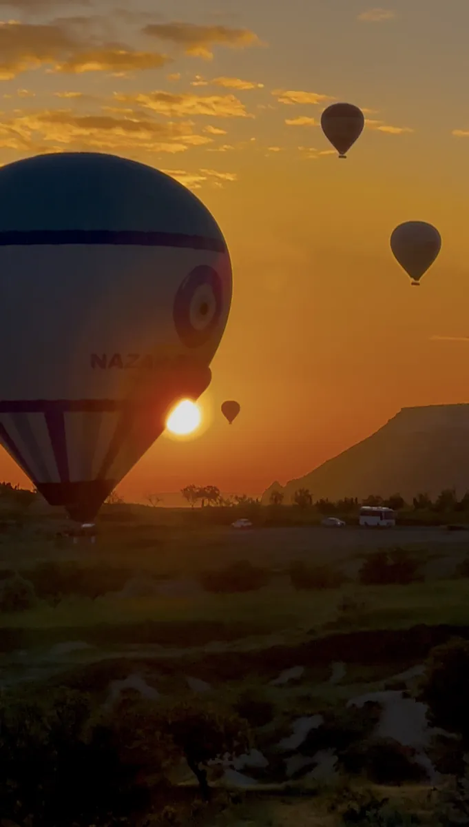 A hot air balloon lifting off at sunrise in Cappadocia