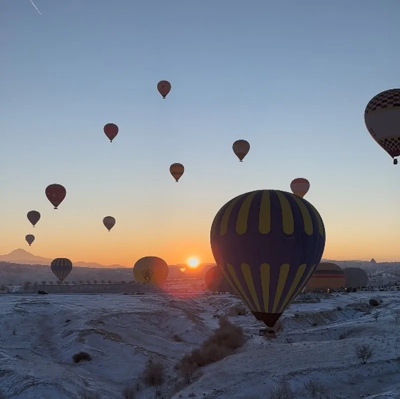 Karla kaplı bir Kapadokya vadisi üzerinde yükselen balon