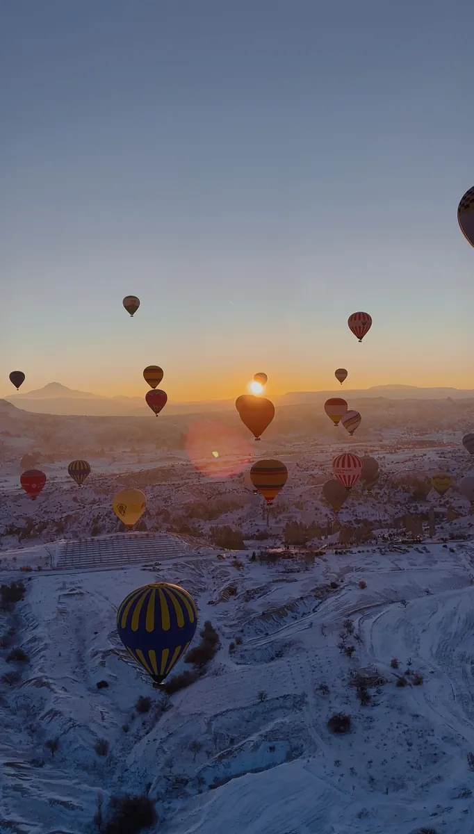 Karlı Kapadokya manzarası üzerinde kış gün doğumu balon uçuşu
