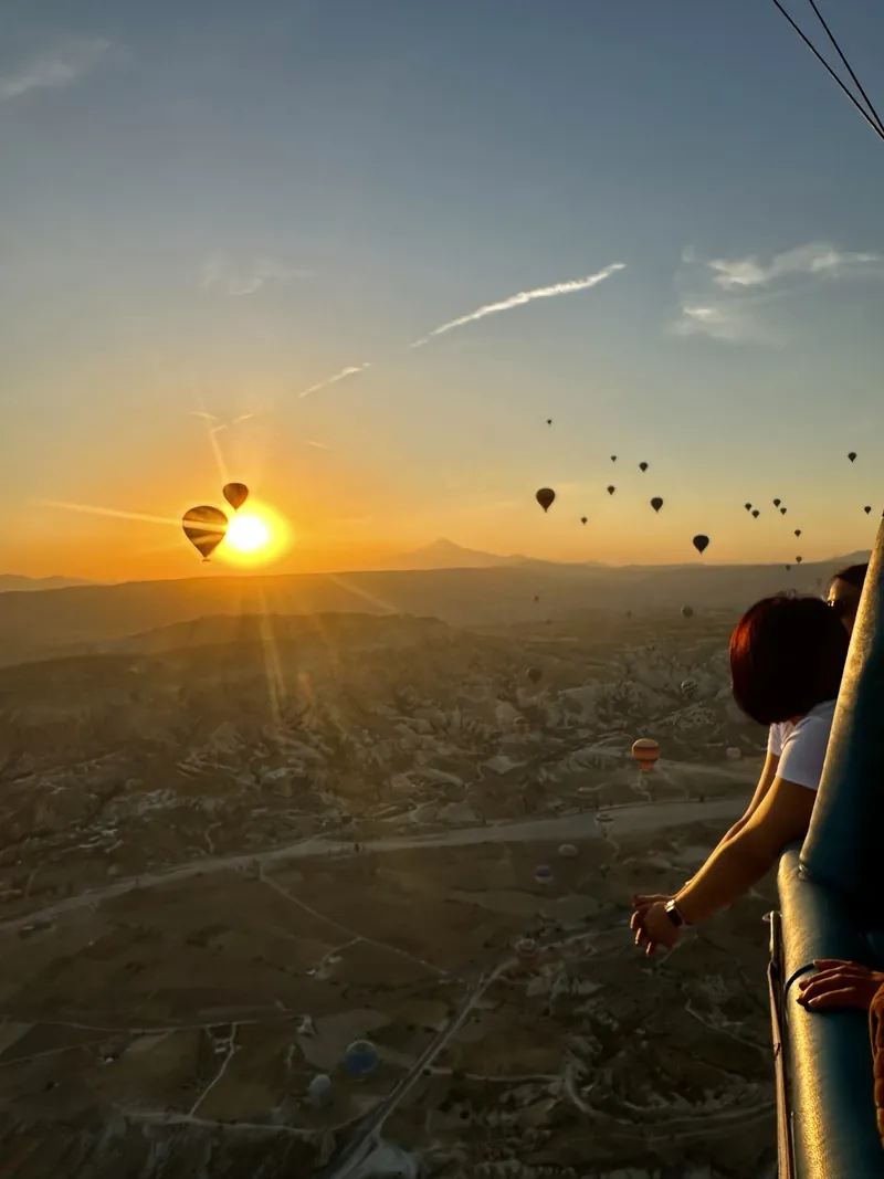 A guest admiring the Cappadocia sunrise from the hot air balloon basket